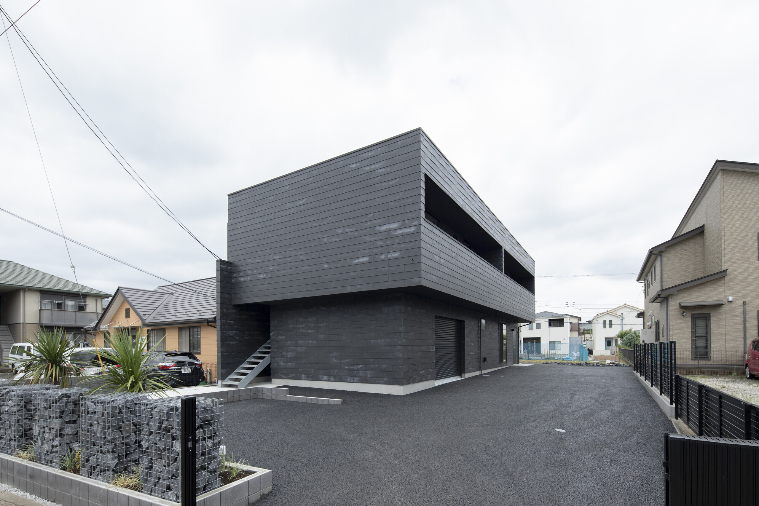 黒いセメントの塊のような事務所併用共同住宅の建築事例写真